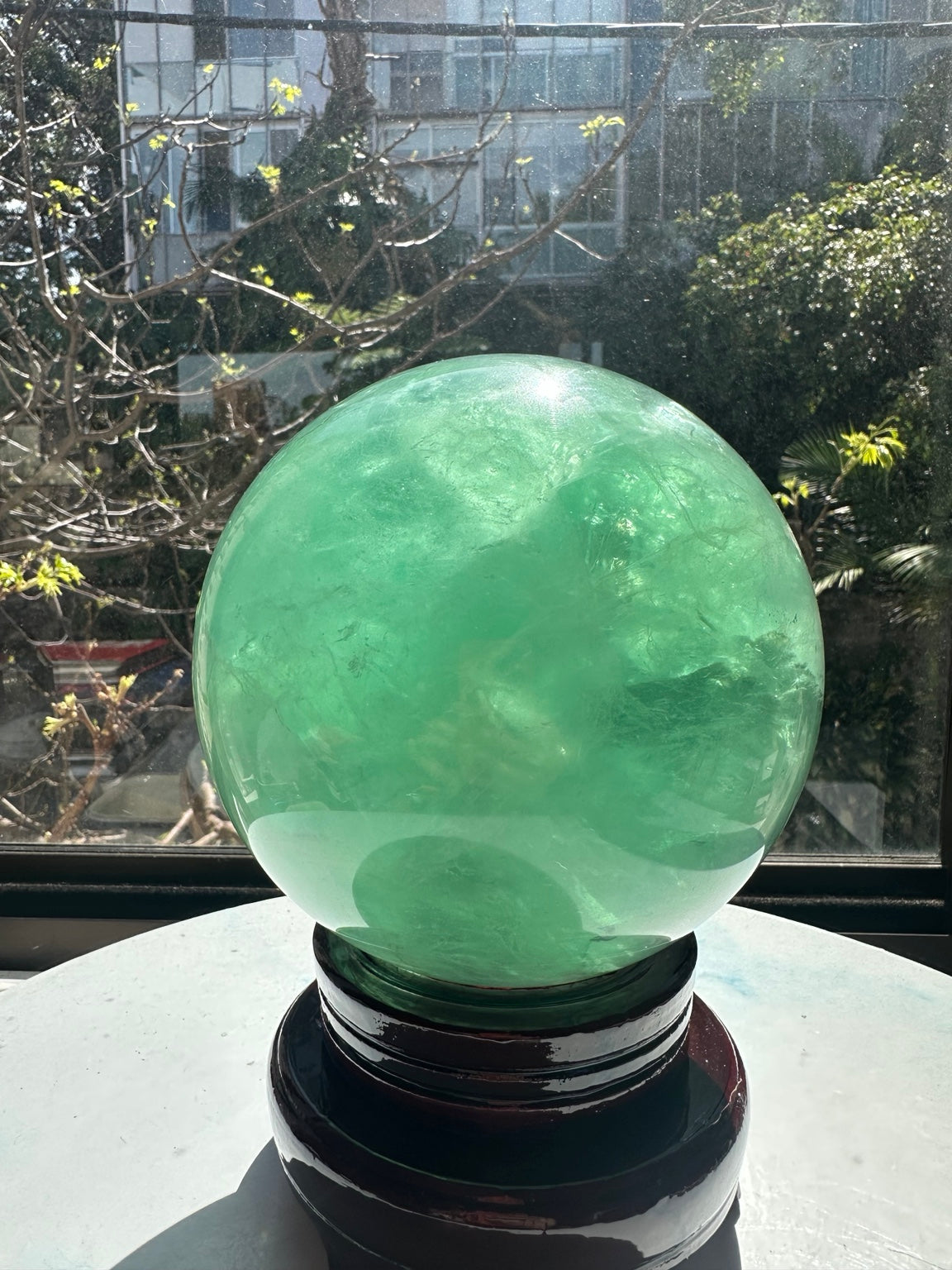 Polished green fluorite sphere with broad mint-green colour, cloudy patches and fine natural internal textures.