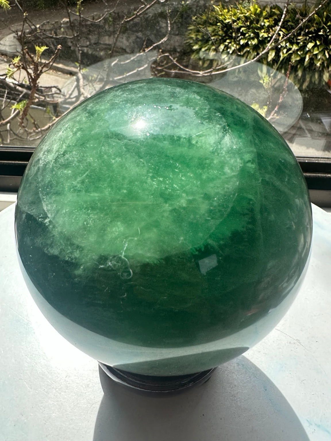 Close view of green fluorite sphere showing green veils and natural texture