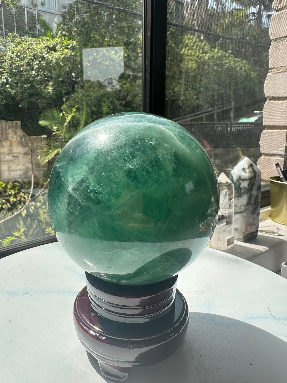 Natural green fluorite sphere translucent pale section and wooden stand
