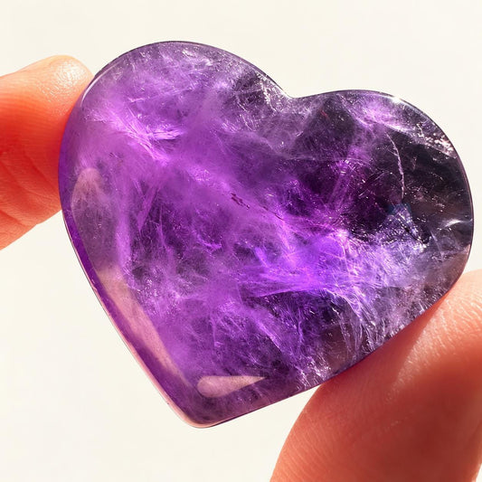 Deep purple amethyst heart in soft indoor light.