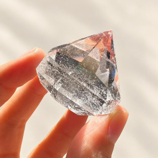 Faceted clear quartz diamond in soft indoor light.