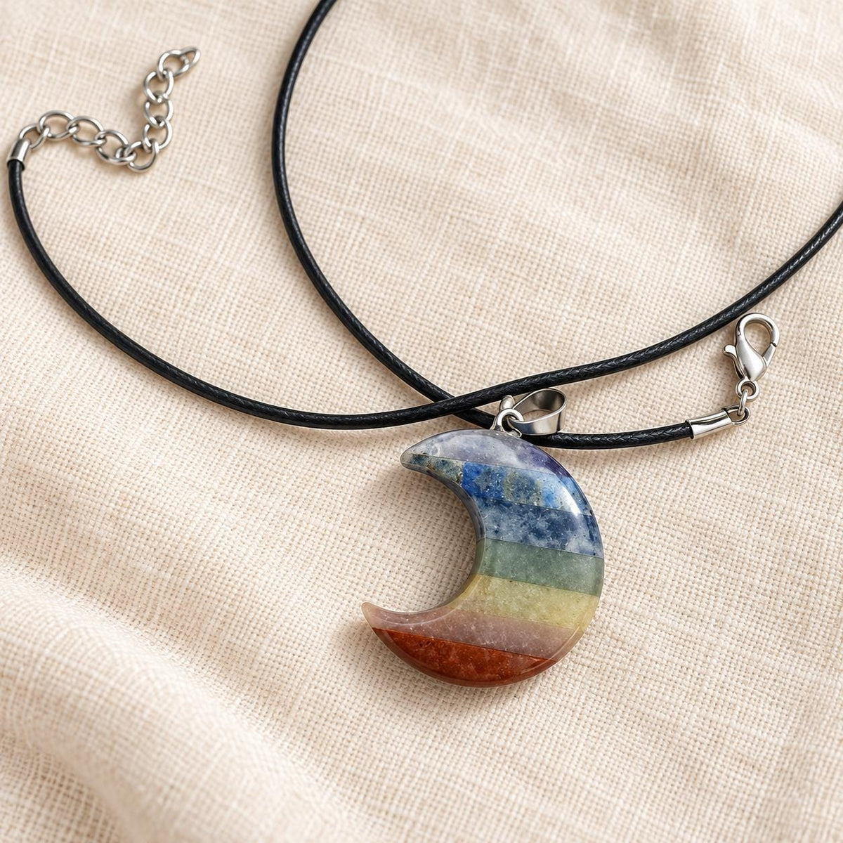 Seven chakra crescent moon crystal necklace with rainbow gemstone bands and black cord, approximately 3.5cm