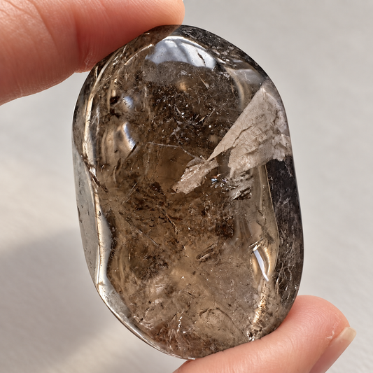 Natural smoky quartz palm stone with translucent tea-brown colour and internal veils