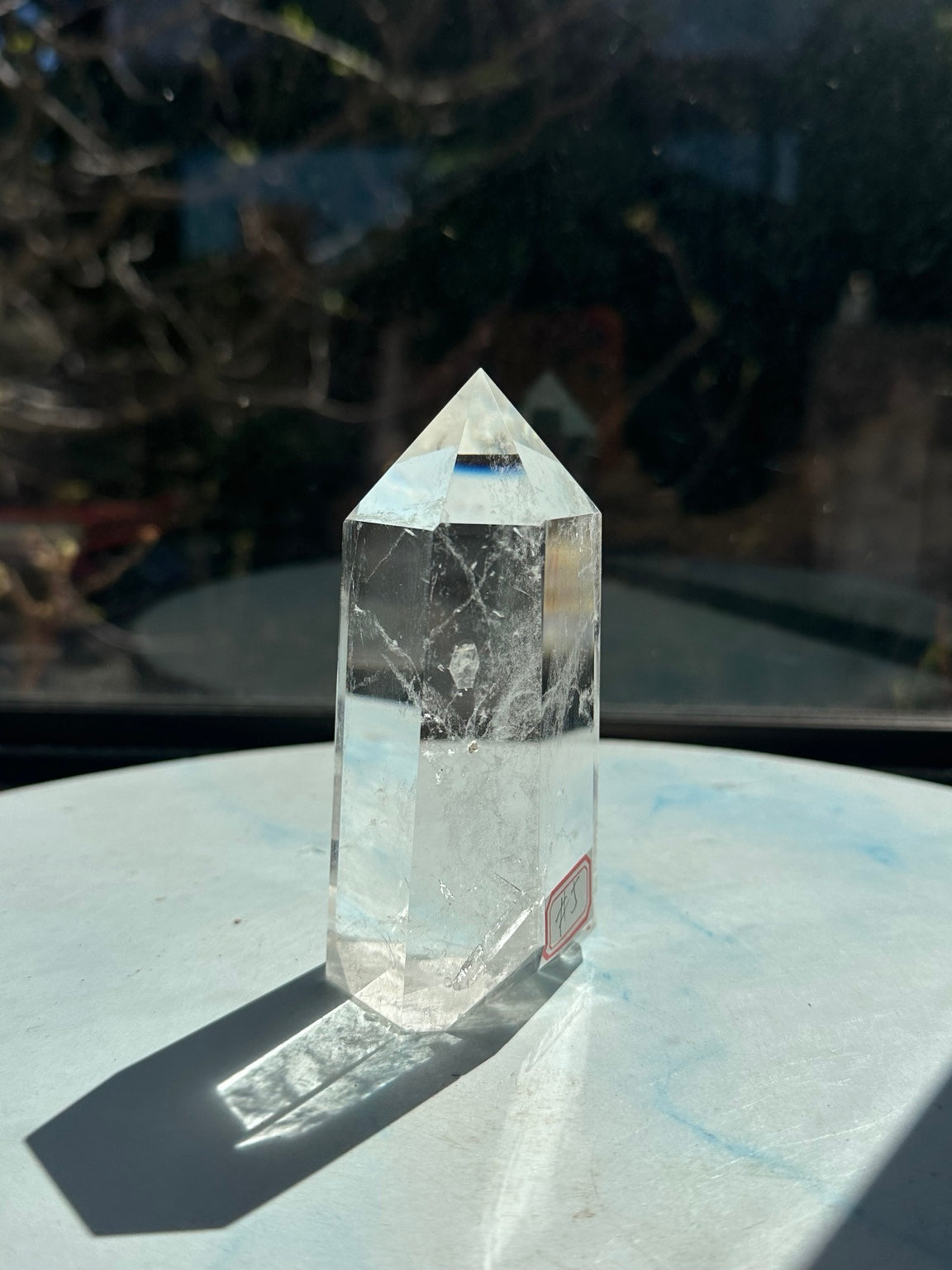 Three-quarter view of clear quartz tower #5 showing its point, base and handwritten number label